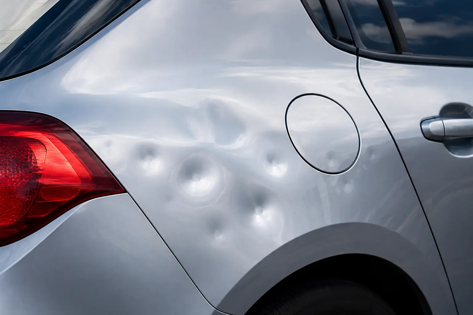 Close-up of hail damage dents on a car door panel